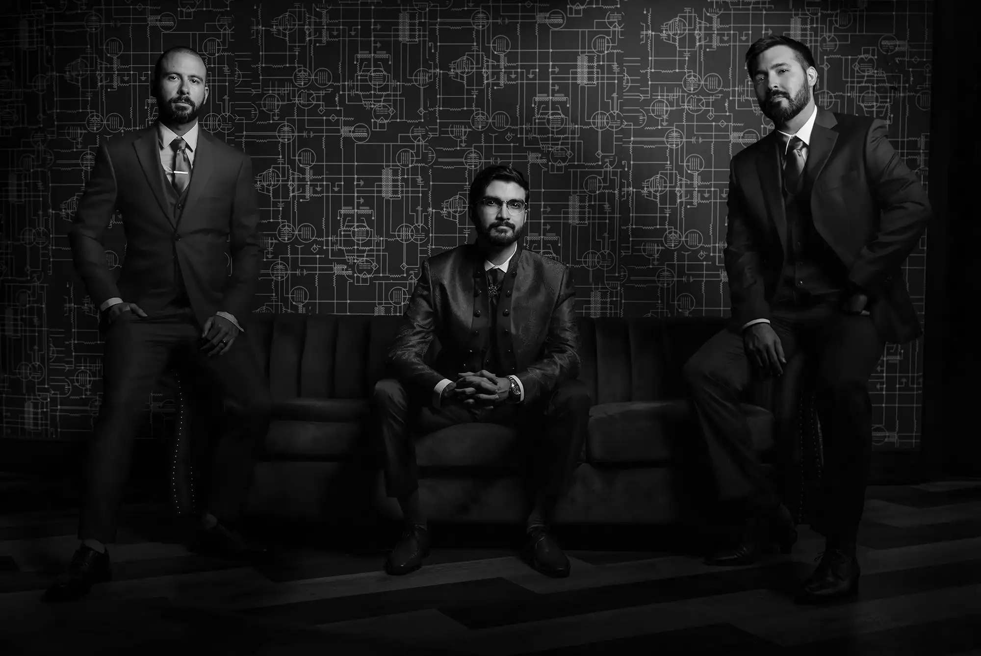 Dramatic black and white image of a groom and groomsmen sitting on a sofa at Aloft Ponce Hotel and Casino