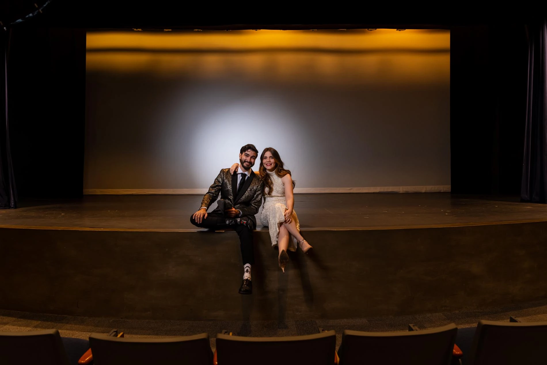 Couple sitting on a stage of an empty theater