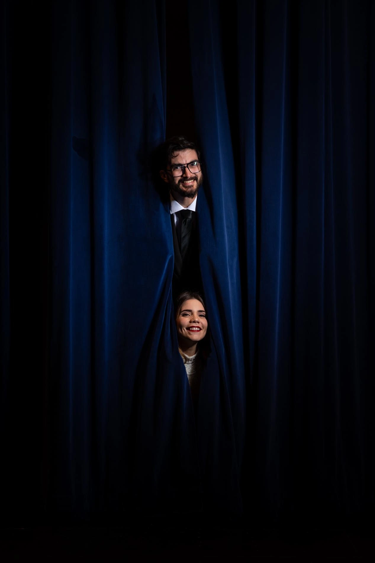 Couple coming out through theater stage curtains