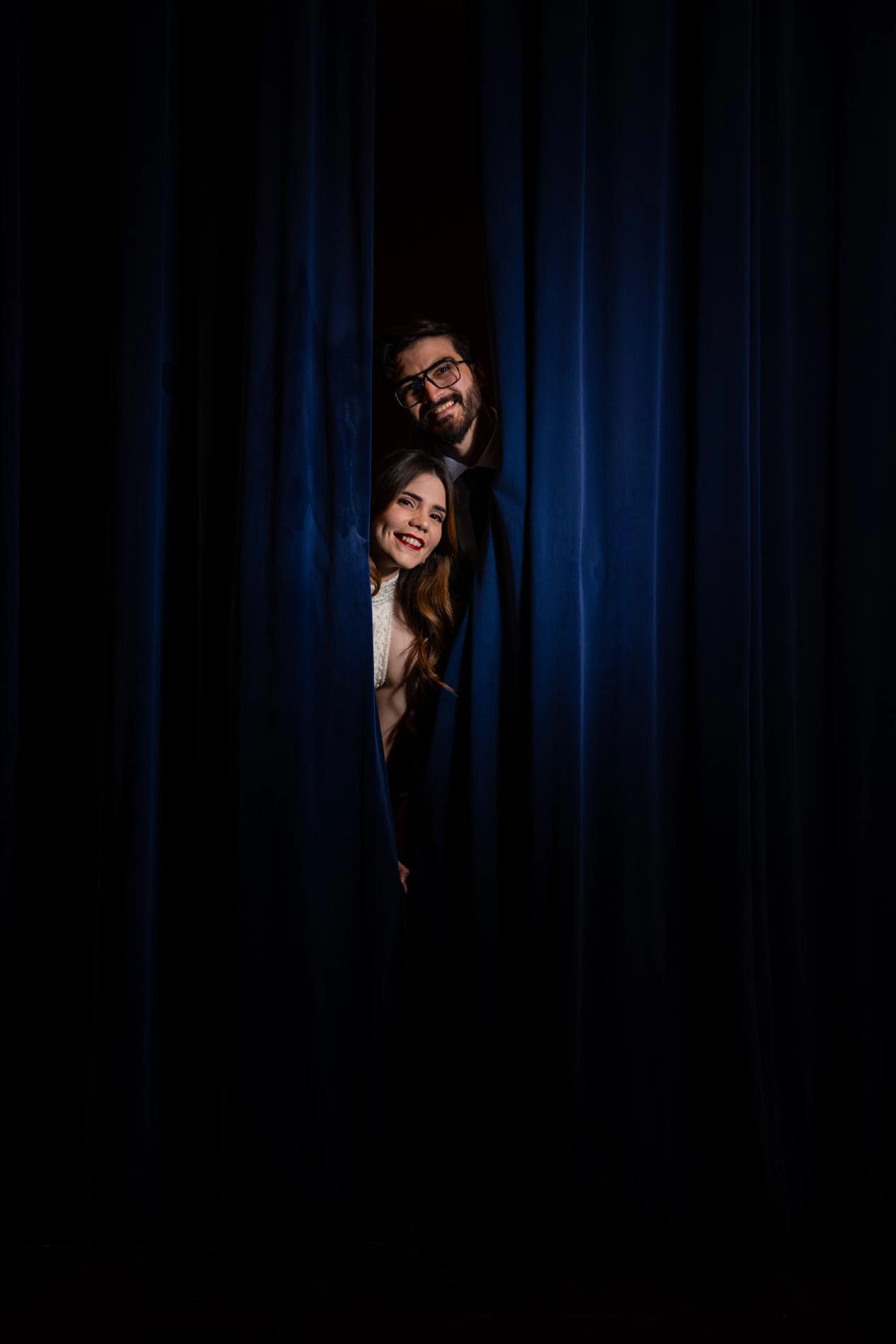 Couple coming out through theater stage curtains