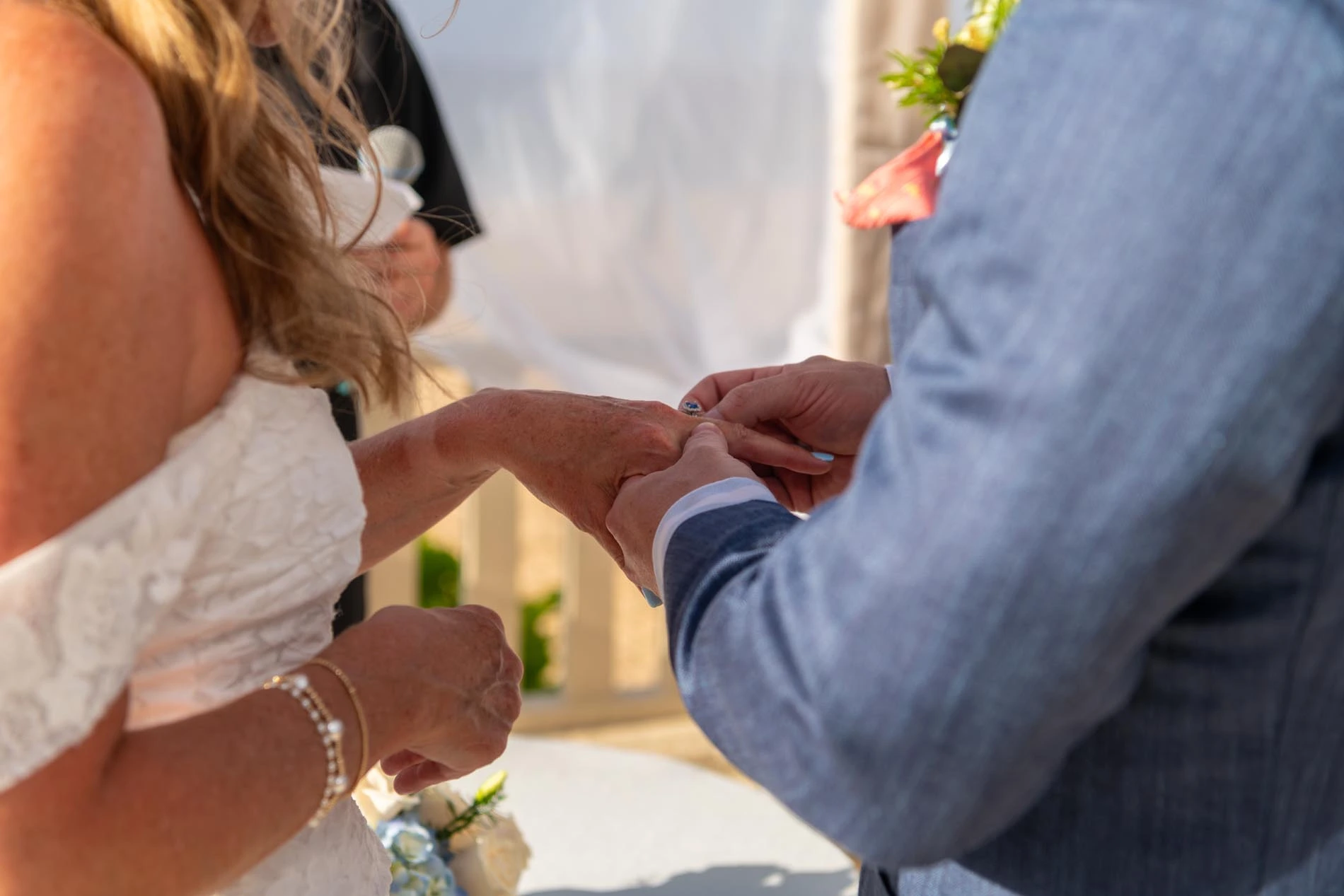 Closeup image of groom putting on the bride's wedding ring