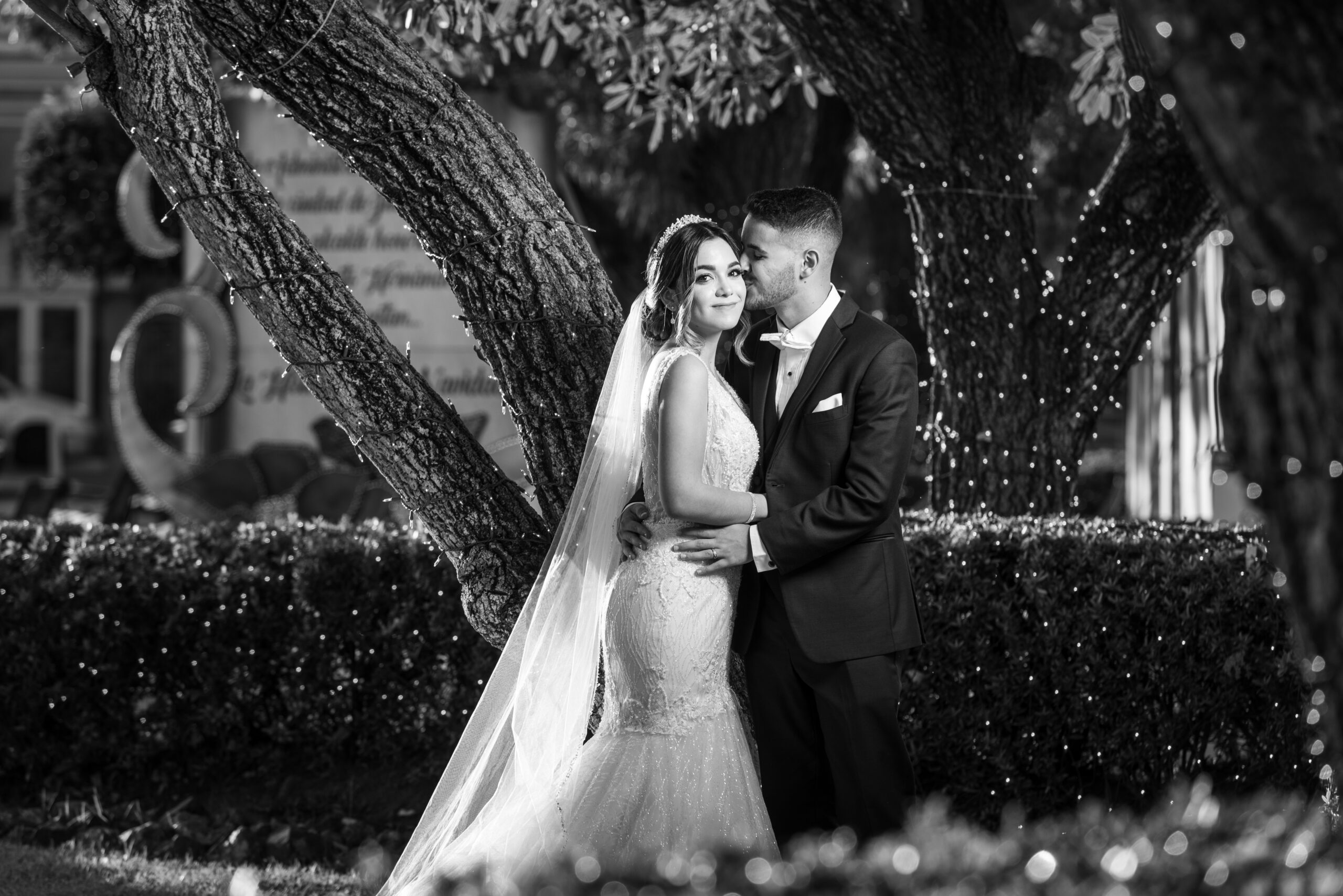 Black and white photo of groom kissing the bride