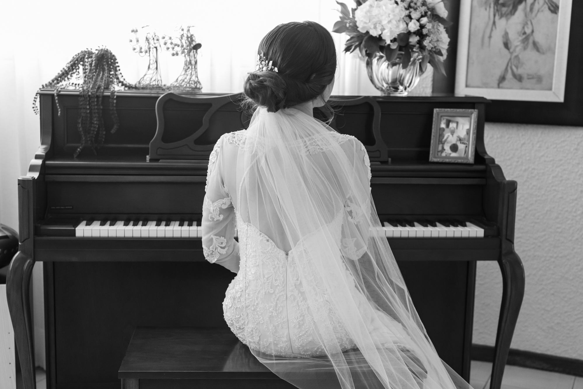 Black and white photo of bride in front of piano