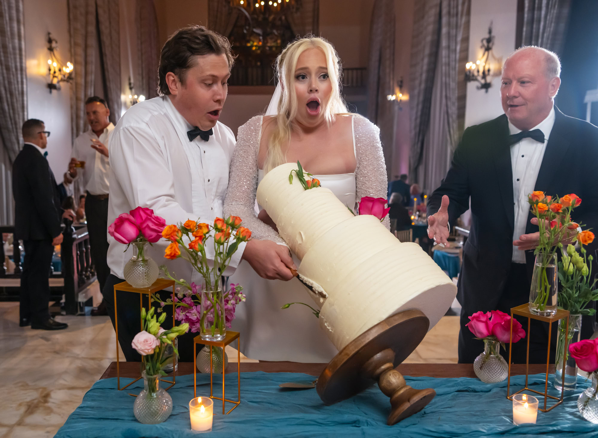 Bride and groom surprised by the fall of the cake and the groom's father tries to help them