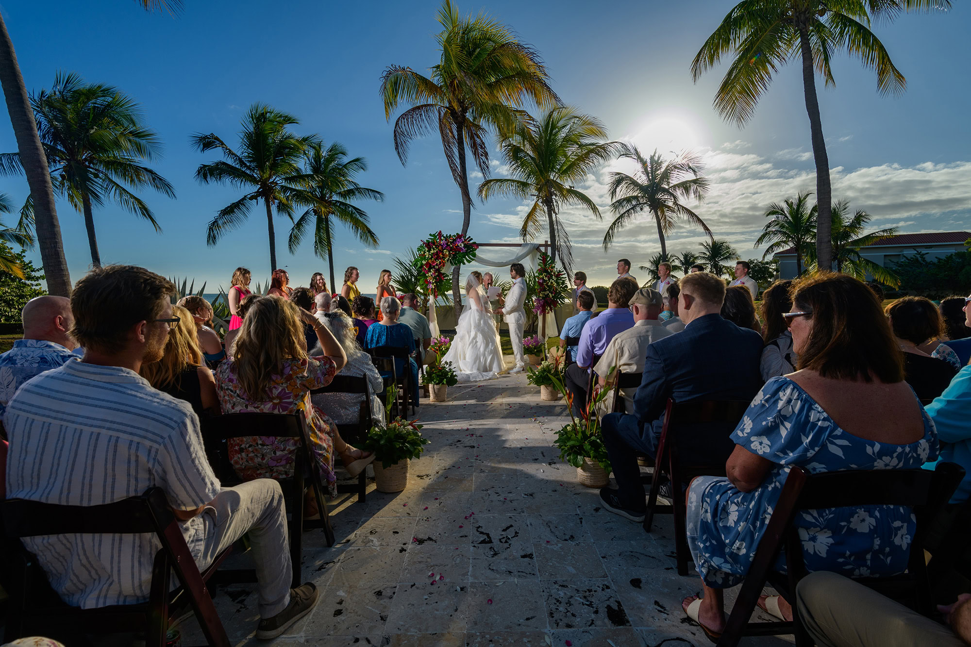 beautiful tropical setting of a couple getting married between palm trees and a blue sky