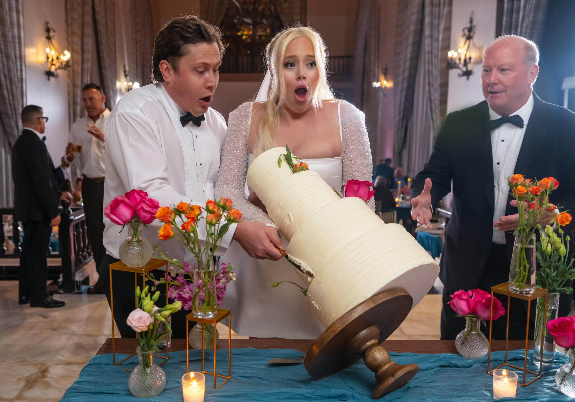 Bride and groom surprised by the fall of the cake and the groom's father tries to help them